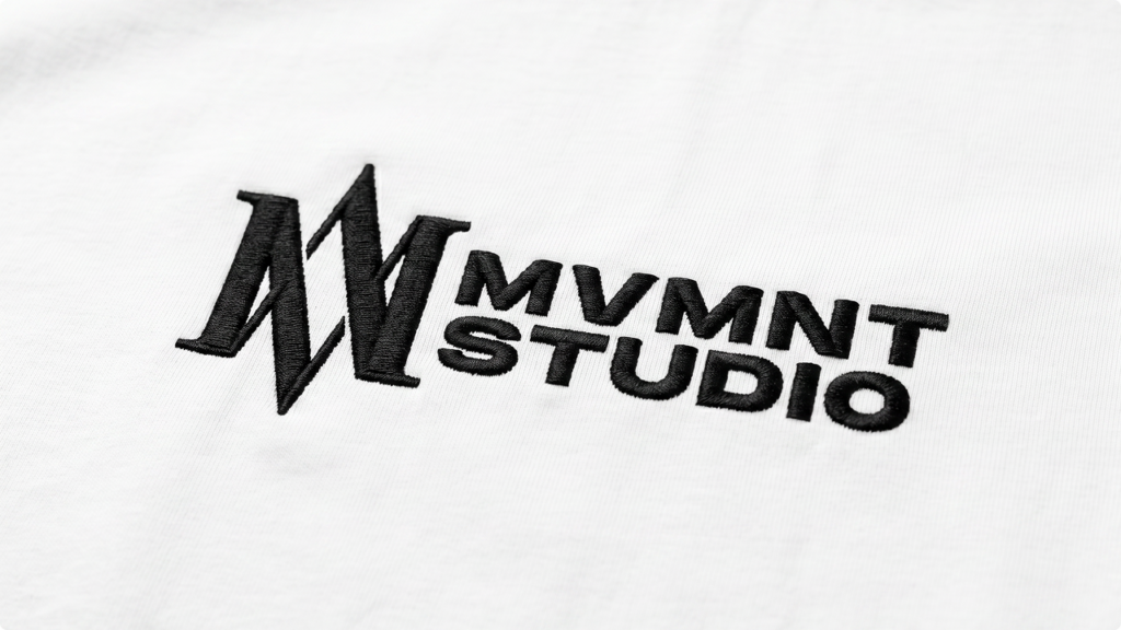 Embroidered logo reading MMNT STUDIO on white fabric
