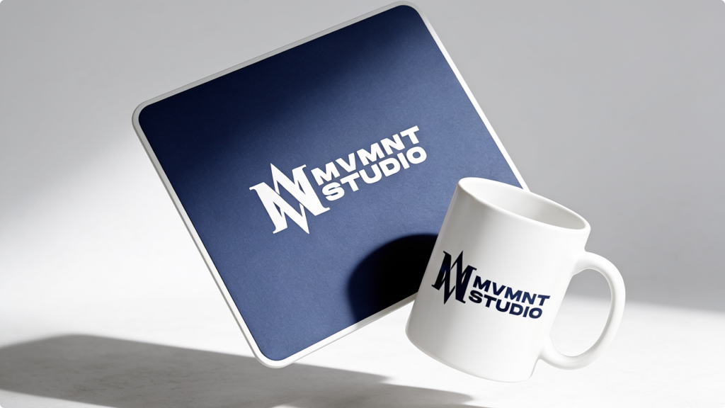 White mug and a tilted blue tablet displaying the MVMNT STUDIO logo.