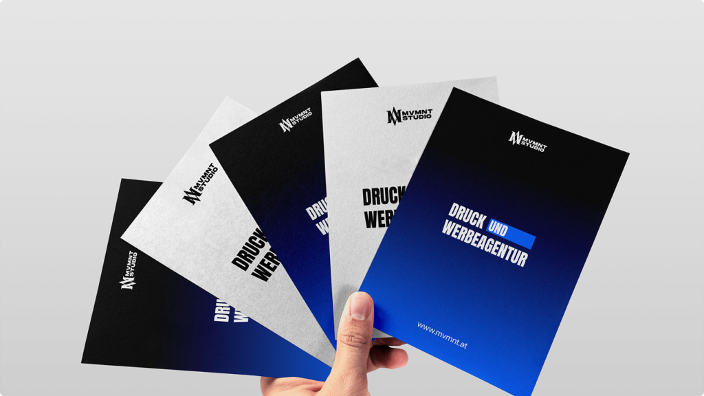 Five fanned-out brochures held in a hand, gradient blue-to-black, reading 'DRUCK UND WERBEAGENTUR' with a small MV MNT Studio logo stacked on top edge of each card