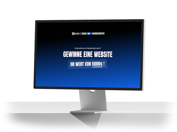 Computermonitor auf einem Schreibtisch zeigt ein blaues Werbebanner: 'GEWINNE EINE WEBSITE IM WERT VON 5000€!'